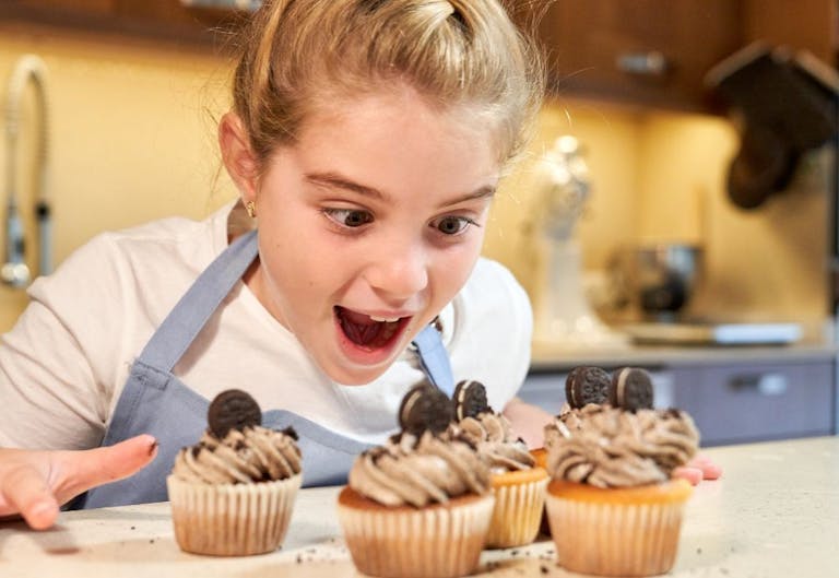 girl looking gleefully at cupcakes