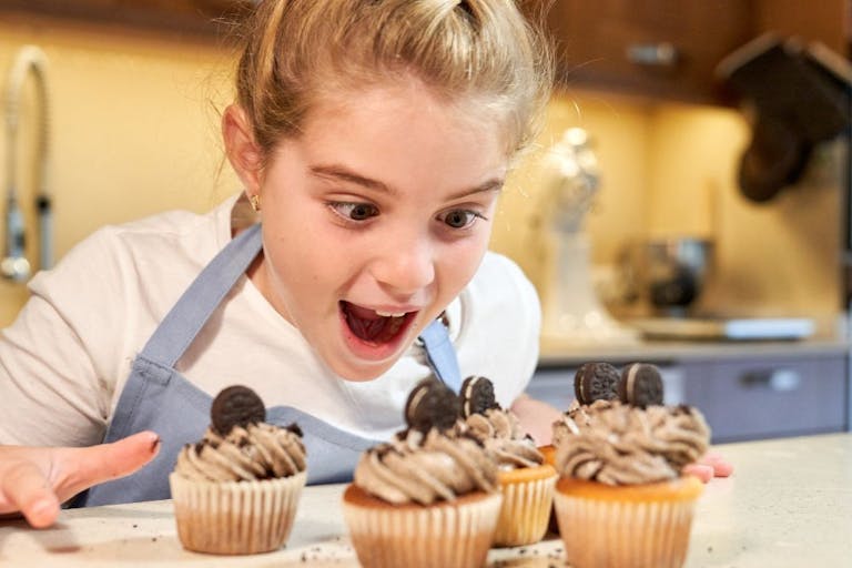 girl looking gleefully at cupcakes