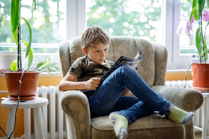 Boy sitting in armchair reading comic