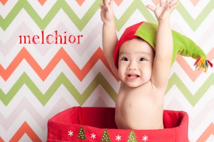 Happy baby with arms in the air wearing an elf hat