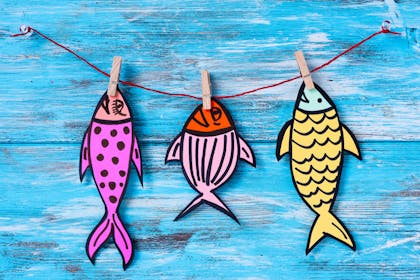 Paper fish cutouts hanging from pegs on string