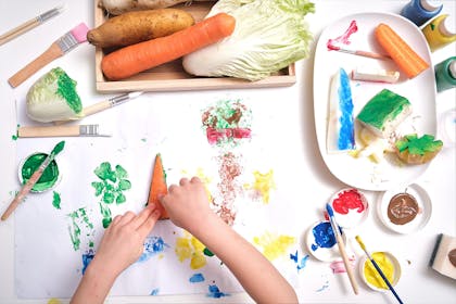 child using different vegetables to paint and print with