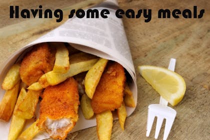 fish and chips wrapped in newspaper on wooden table