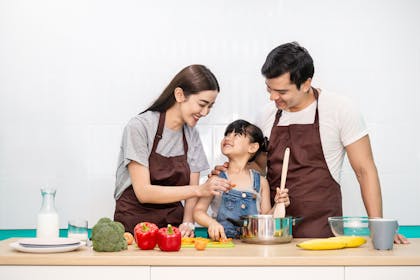 Young Asian girl cooking with her parents