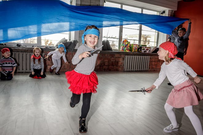 Girls dressed as pirates running under blue fabric that looks like the sea