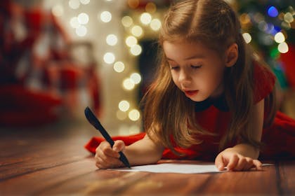 girl in red dress writing a letter to Santa