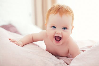 Red haired baby crawling on bed