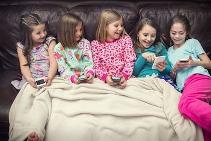 Girls watching movie and playing on phones at sleepover