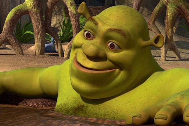 Shrek sitting in a mud bath smiling
