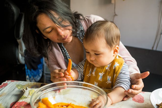 mum helping baby learn to eat new tastes