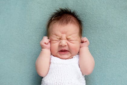 Newborn baby with a full head of hair and screwed up face