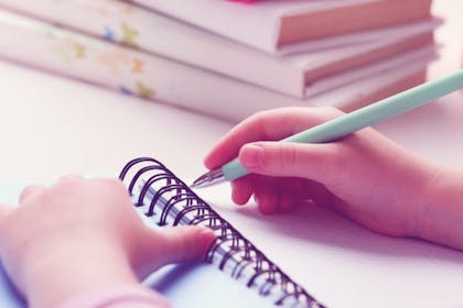 child writing in notebook