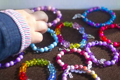 Kid reaching for pile of handmade bead bracelets