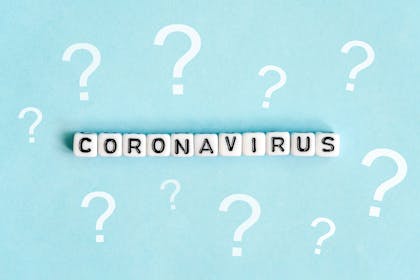 Coronavirus written on beads on pale blue background surrounded by question marks