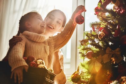 Mother and daughter hanging decorations on the Christmas tree 