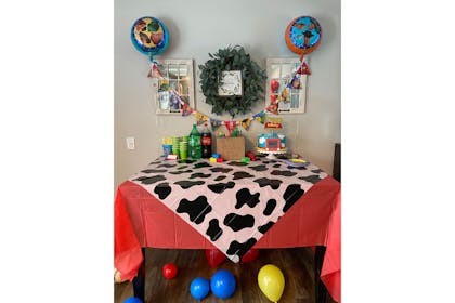 Toy Story party table with cow print tablecloth and blue and yellow balloons