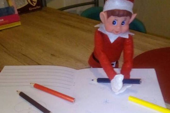 Christmas Elf on the shelf drawing pictures with coloured pencils