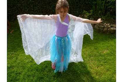 A kid dressed as Elsa poses in a blue tutu, lilac top and chiffon cloak