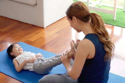 Mum doing yoga with girl on mat on floor