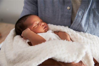 Baby in blanket held by father 