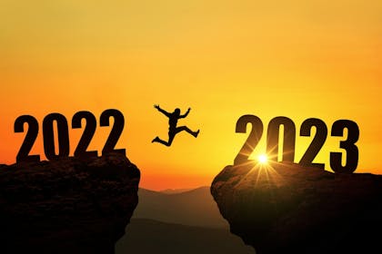 Man jumping from cliff with 2022 on it to cliff with 2023 on it