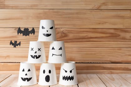 White paper cups with ghostly faces drawn on