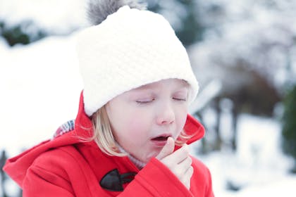 Young girl coughing outside in winter