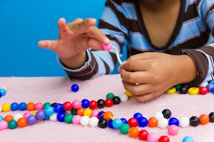 A child making jewellery with colourful beads