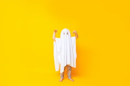 Child dressed up as ghost using white bedsheet 