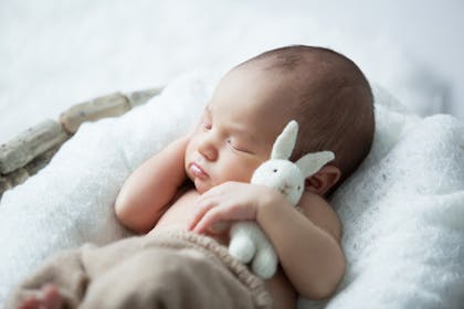 newborn baby sleeping and holding a bunny