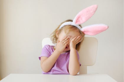 Toddler plays peekaboo while wearing bunny ears as Halloween party costume