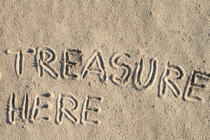 the words 'treasure here' written in sand