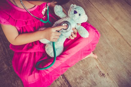 Girl listening to teddy's heart with stethoscope