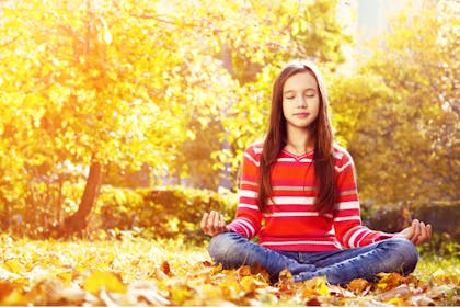 Teenager meditating outside in autumn