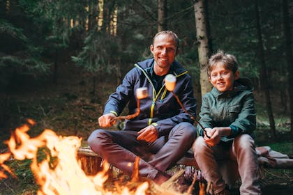 Father and son toasting marshmallows over campfire