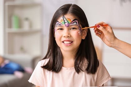 Young girl having unicorn face paint applied