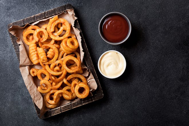 Tray of curly fries with ketchup and mayonnaise