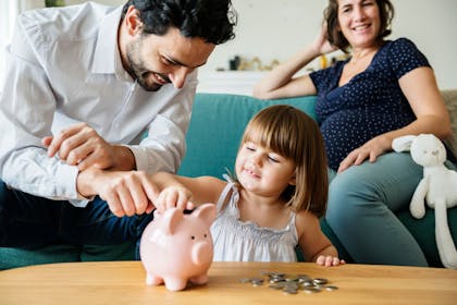Family with child putting money into piggy bank