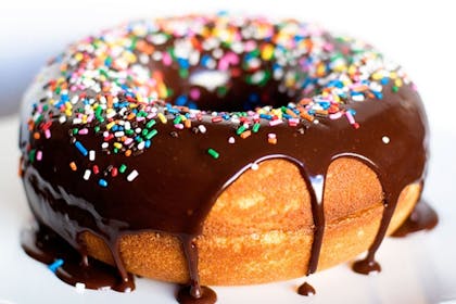 Cake in shape of doughnut covered in chocolate icing and sprinkles 