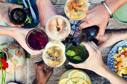 hands reaching in to cheers with various alcoholic drinks