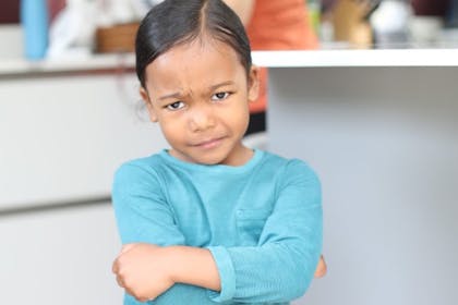 Young girl looking grumpy as she holds her arm