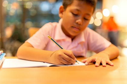 Schoolboy writing on paper at a desk