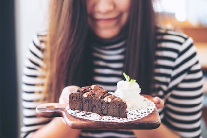 woman holding plate with chocolate cake