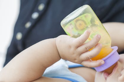 baby drinking orange juice from bottle
