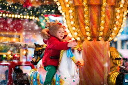 A Little girl rides a carousal horse at xmas event 