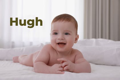Baby lying on front on bed smiling. Name Hugh written in text