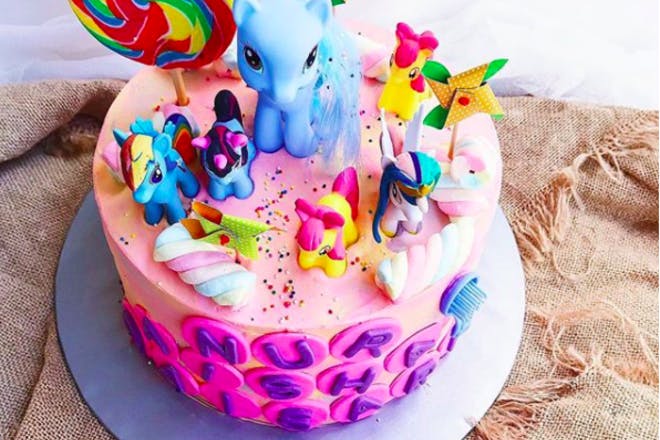 Pink cake with My Little Pony toys on top