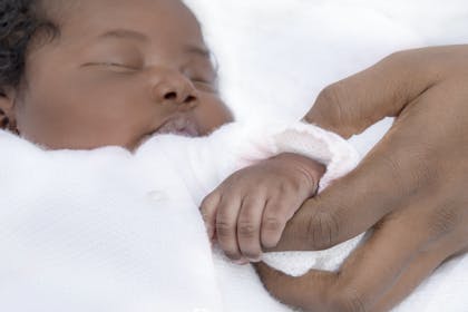 Baby asleep holding hands with mother