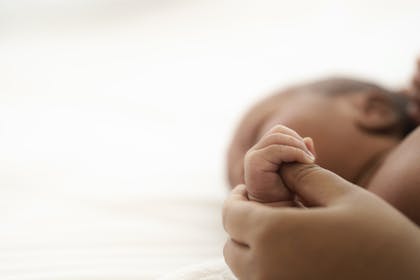 Close up of newborn baby holding hands with parent