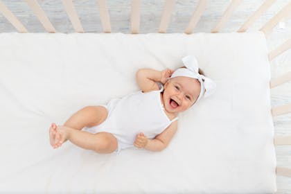 Baby girl lying in crib smiling